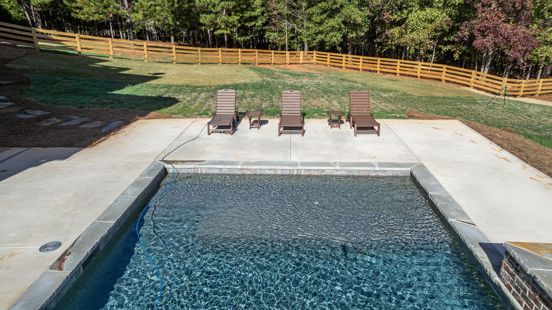 A swimming pool surrounded by chairs and a wooden fence