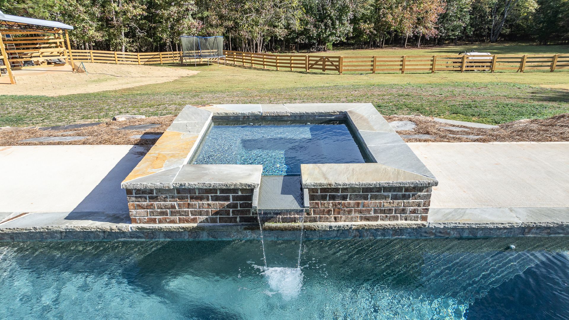 A swimming pool with a hot tub in the middle of it.