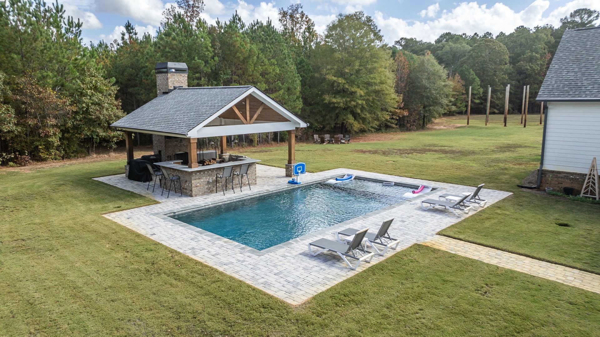 There is a large swimming pool in the middle of a lush green field.