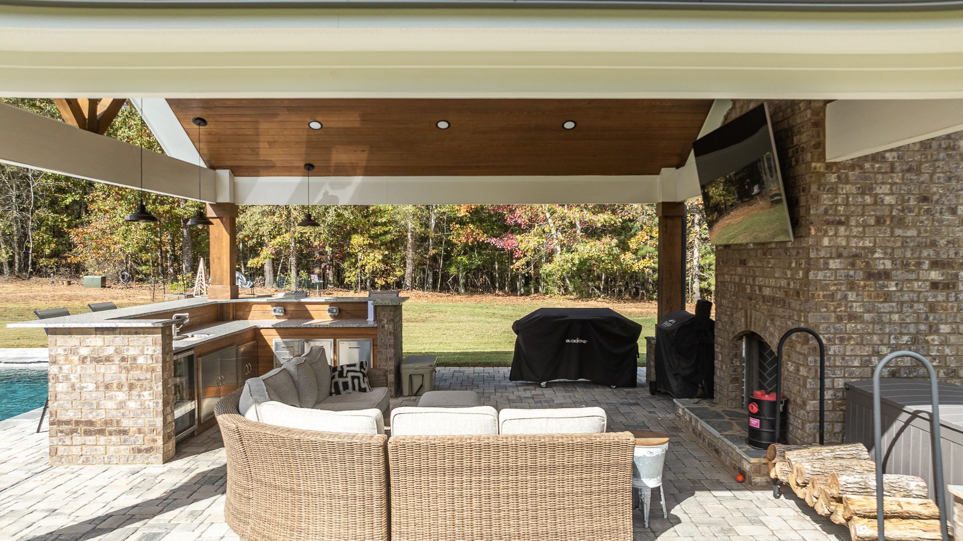 A patio with a couch and a television on the wall.