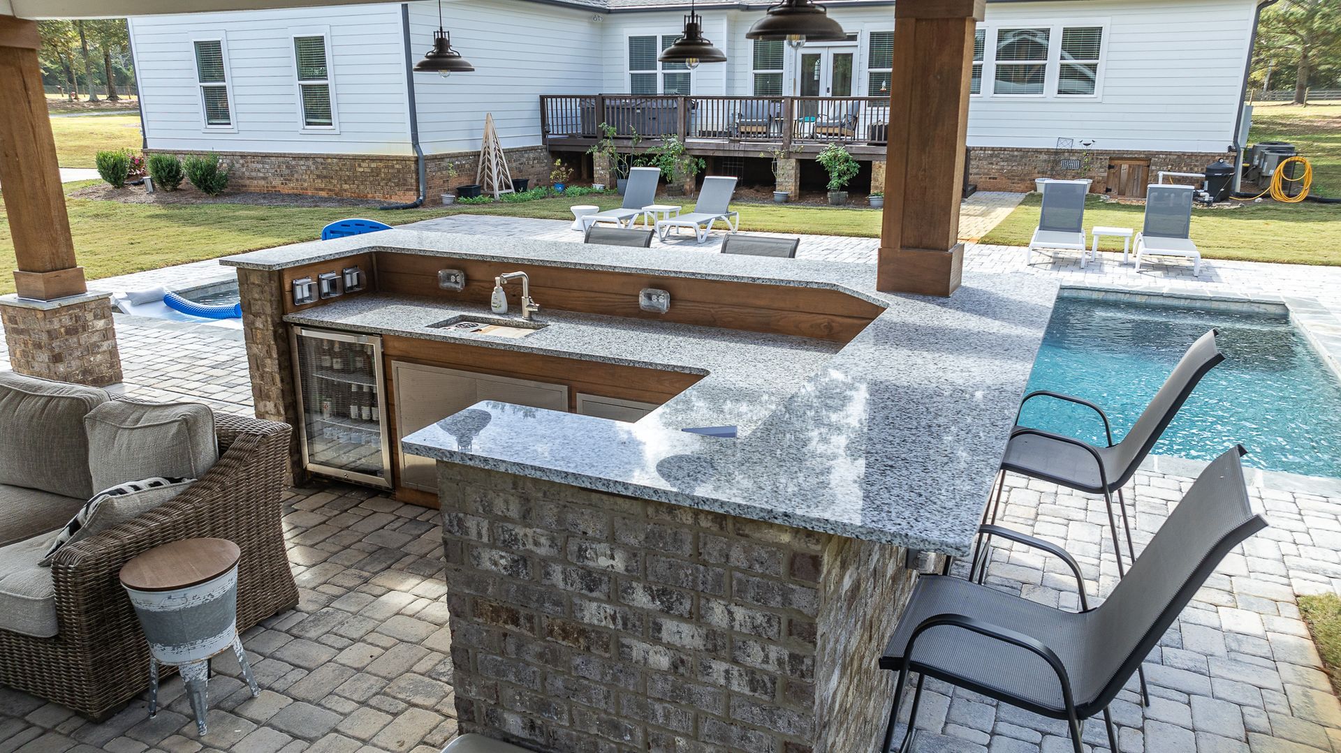 A large outdoor kitchen with a swimming pool in the background.