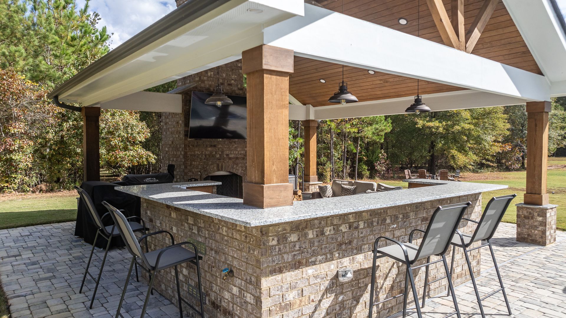A large outdoor kitchen with a bar and chairs under a canopy.