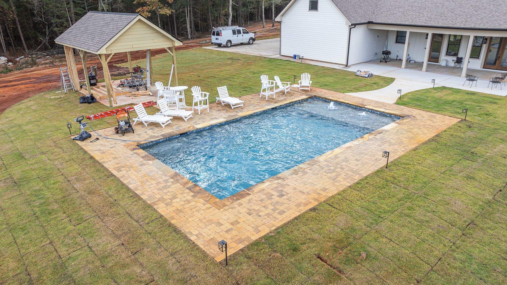 An aerial view of a large swimming pool in front of a house.