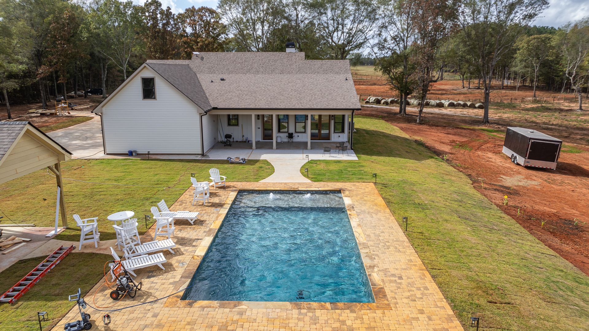 An aerial view of a house with a large swimming pool in the backyard.