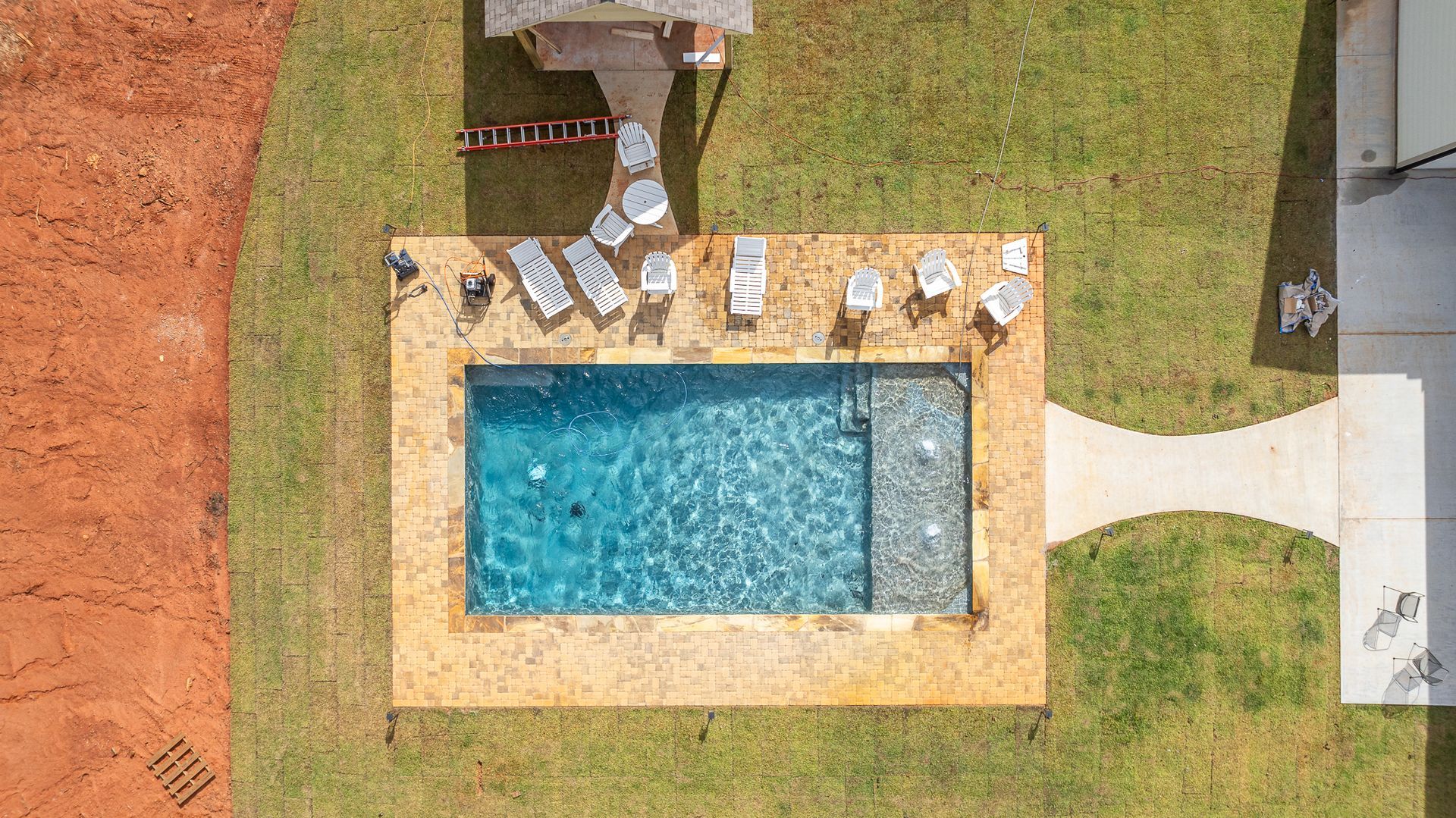 An aerial view of a large swimming pool surrounded by grass and chairs.