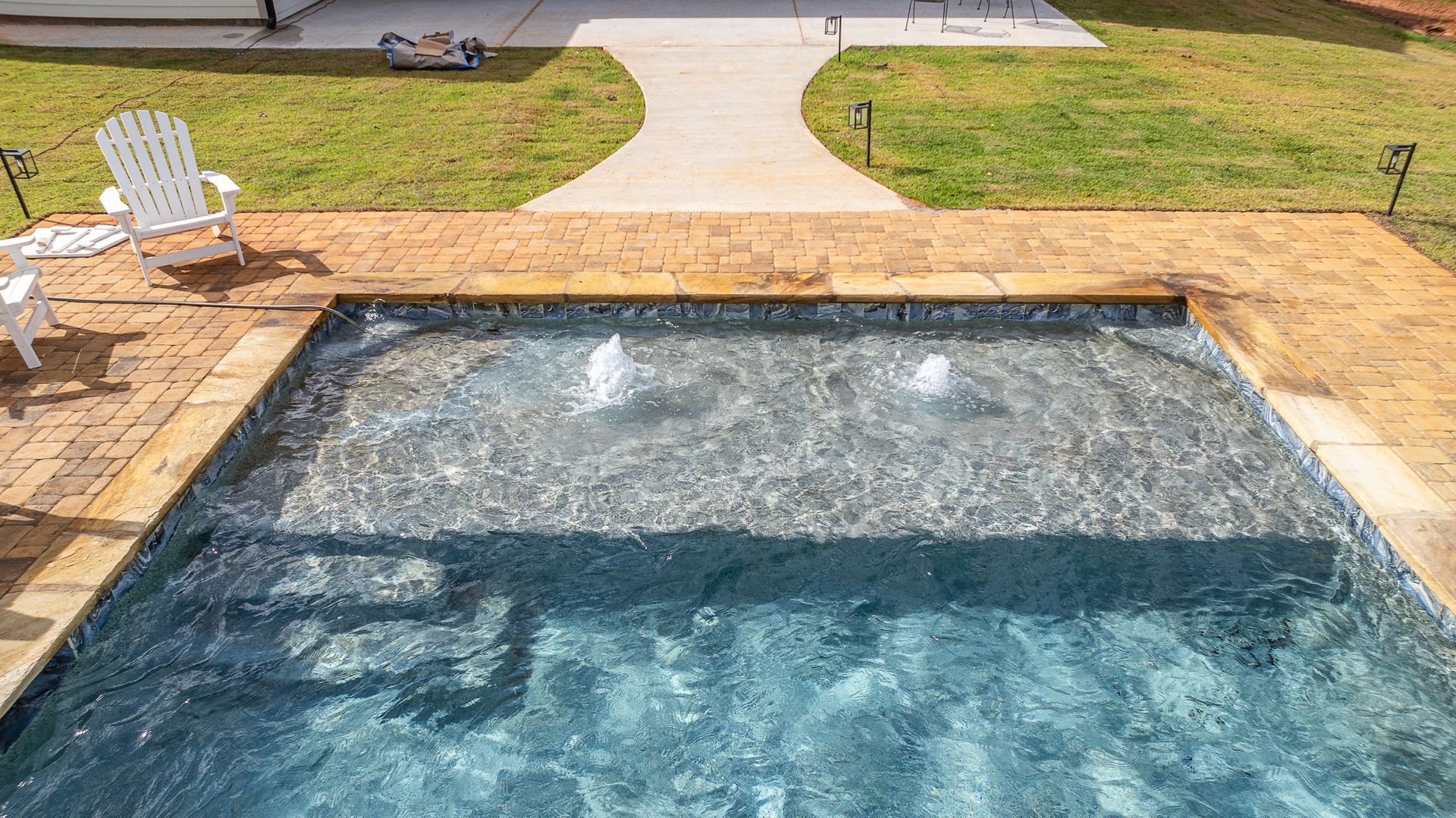 There is a swimming pool with a fountain in the middle of it.