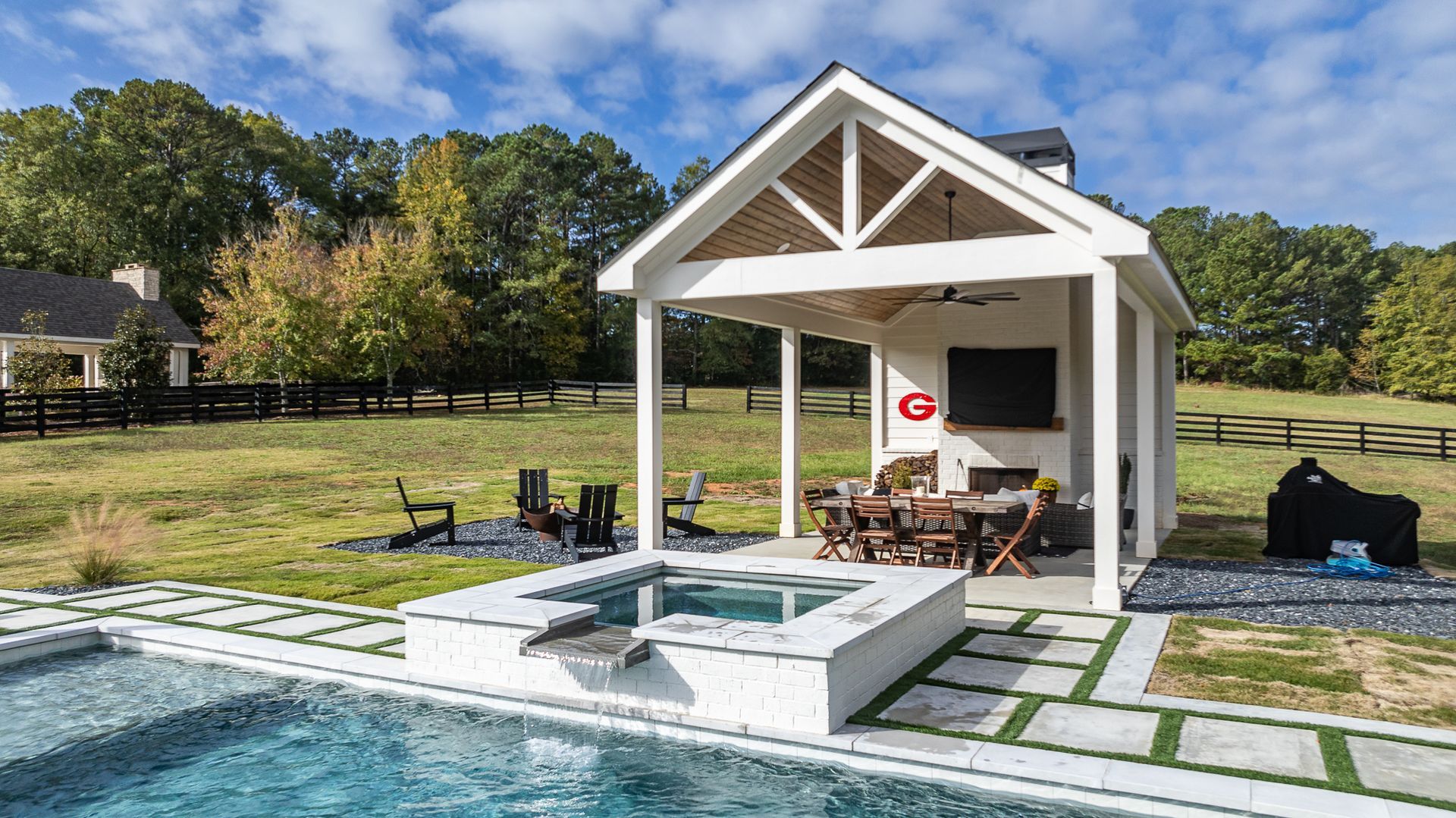 A swimming pool with a gazebo and a table and chairs in front of it.
