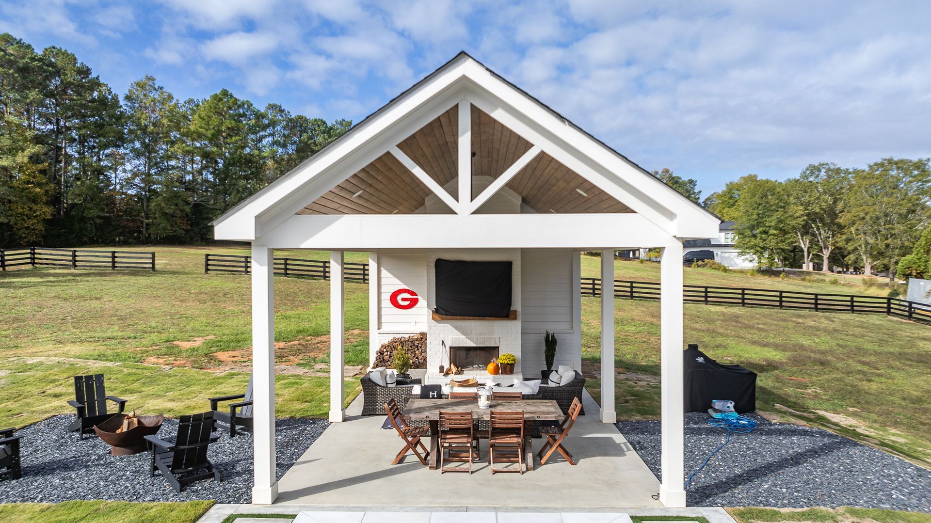A white pavilion with a table and chairs underneath it in a field.
