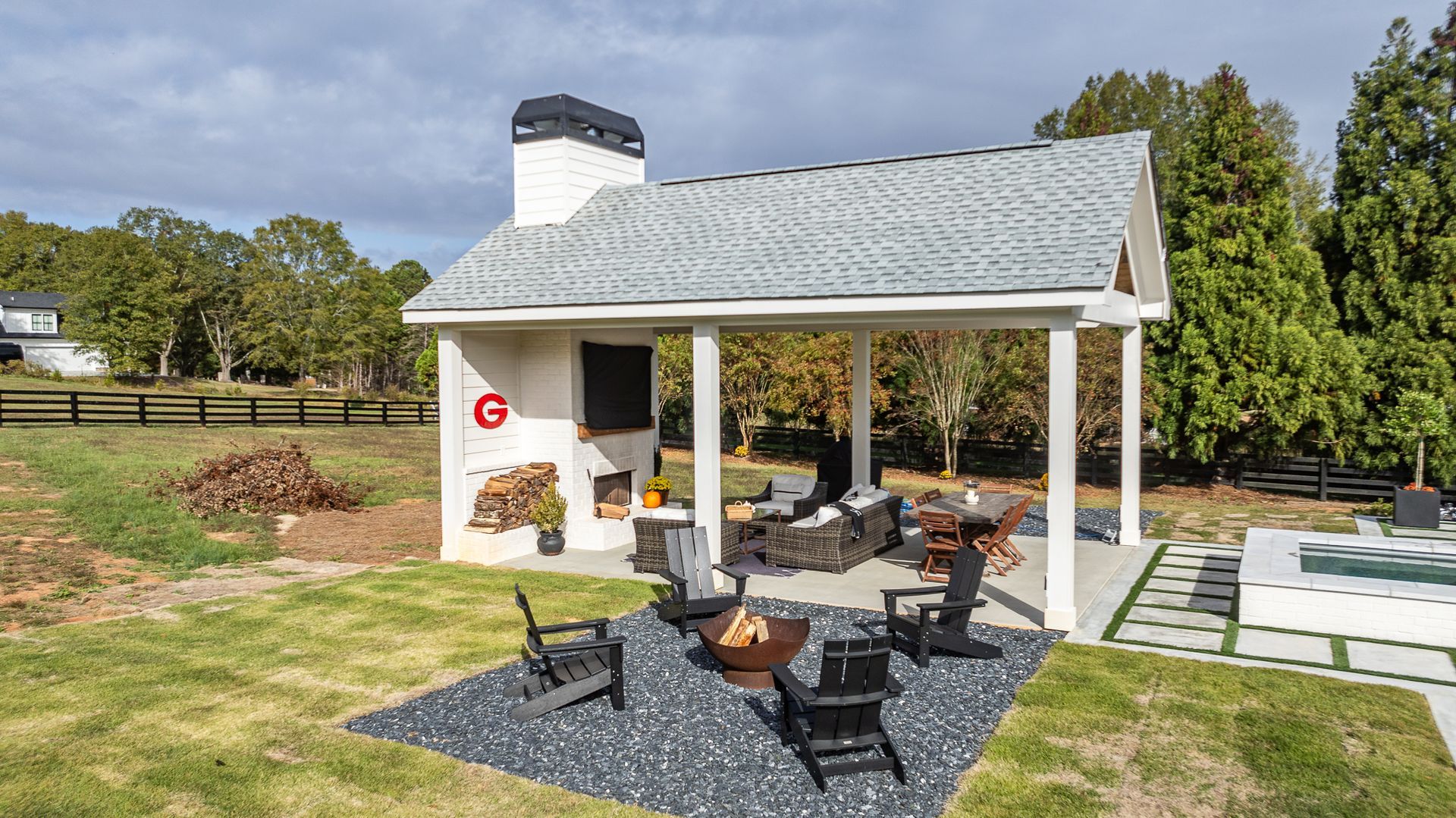 There is a pavilion with a fireplace and chairs in the backyard.