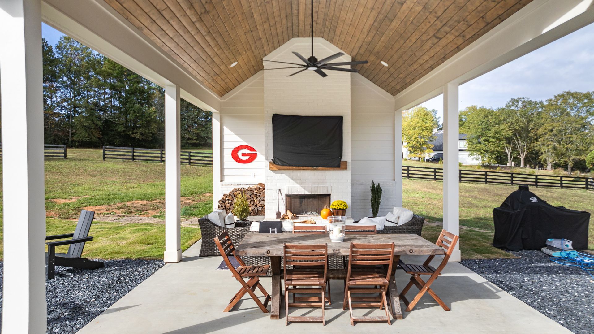 A covered patio with a table and chairs and a fireplace.