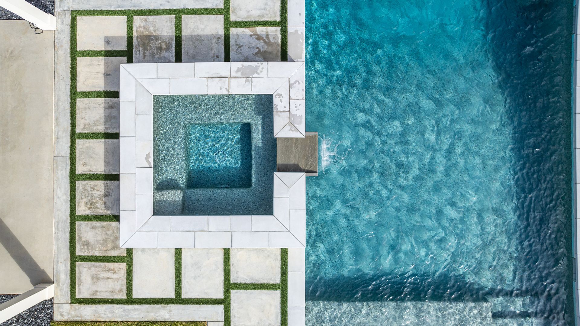 An aerial view of a large swimming pool with a hot tub in the middle.