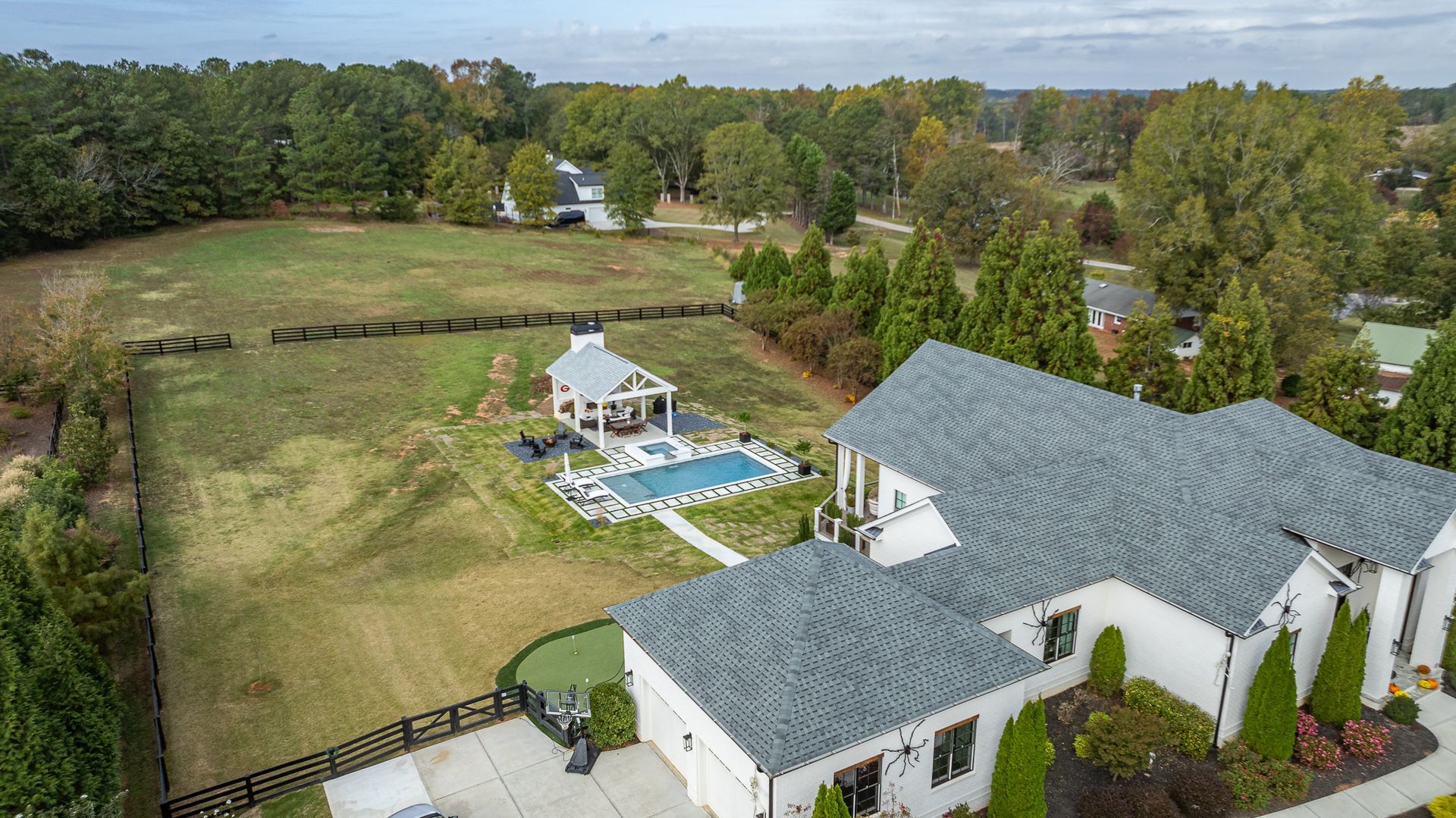 An aerial view of a large house with a pool in the backyard surrounded by trees.