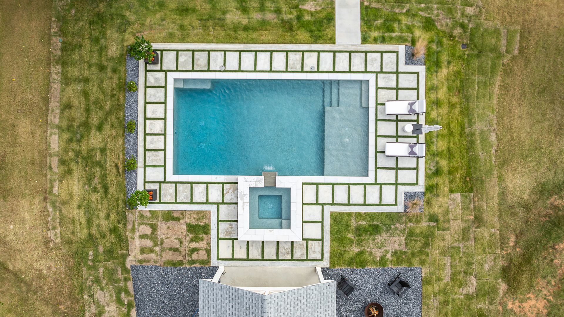 An aerial view of a large swimming pool surrounded by a lush green lawn.