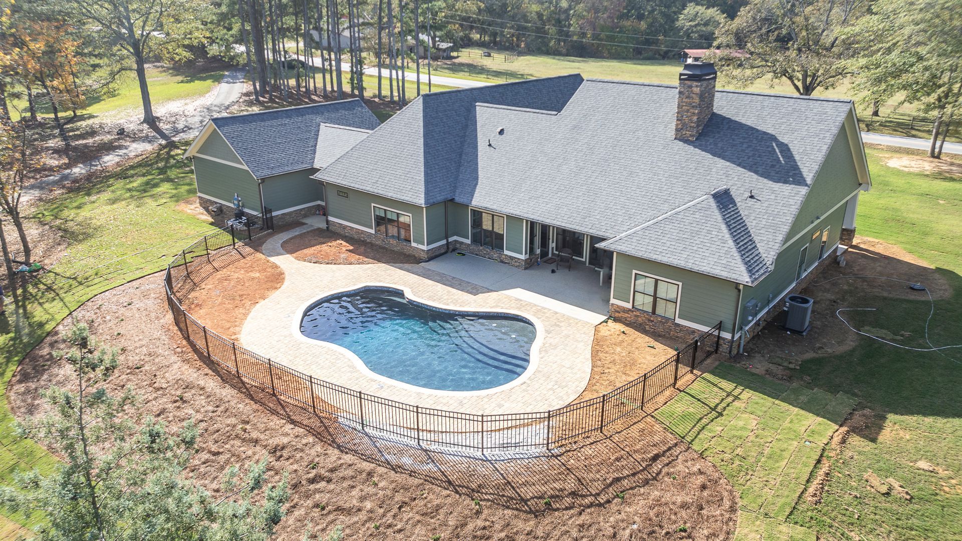 An aerial view of a house with a large pool in the backyard.