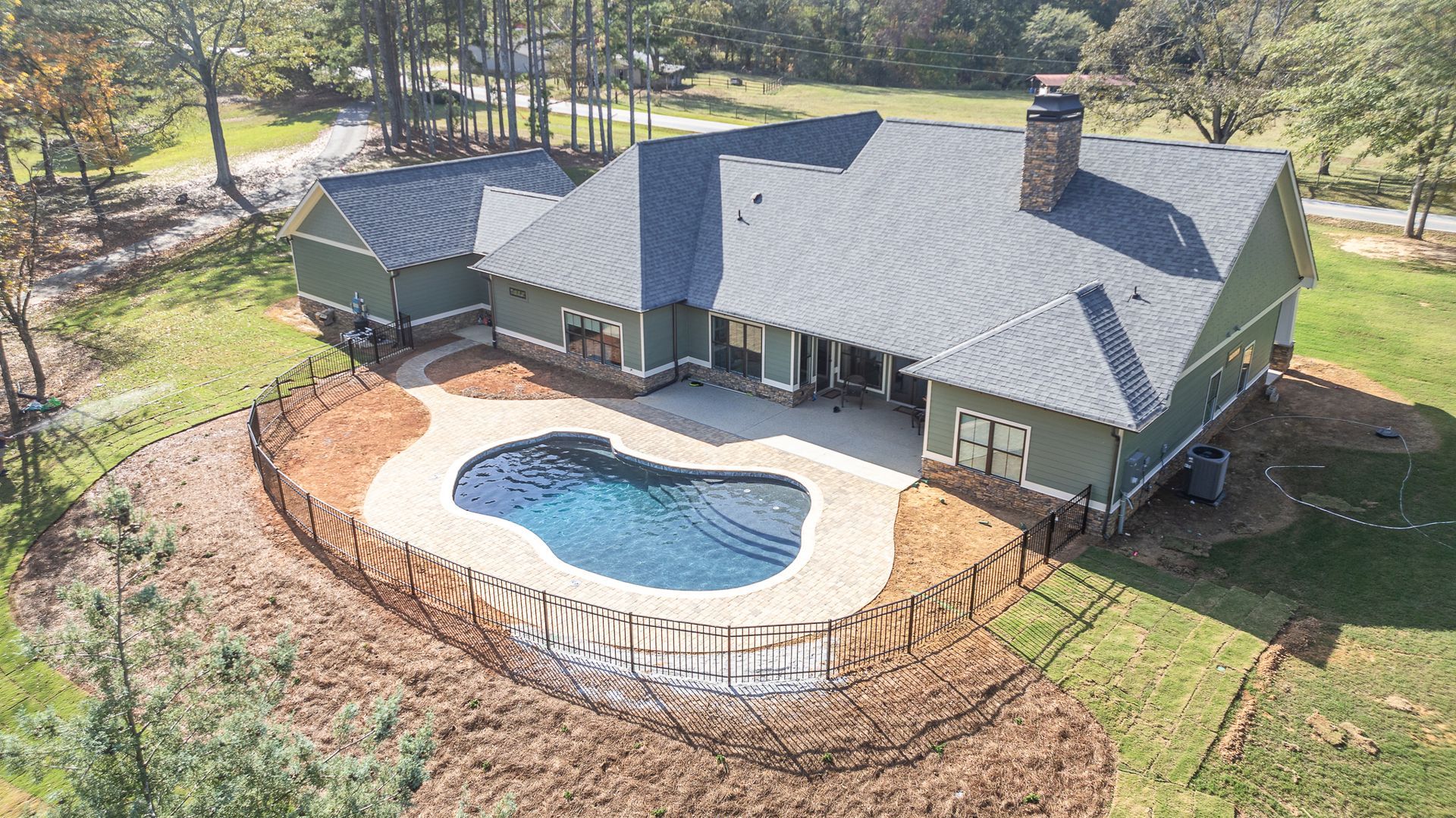 An aerial view of a house with a large pool in the backyard.