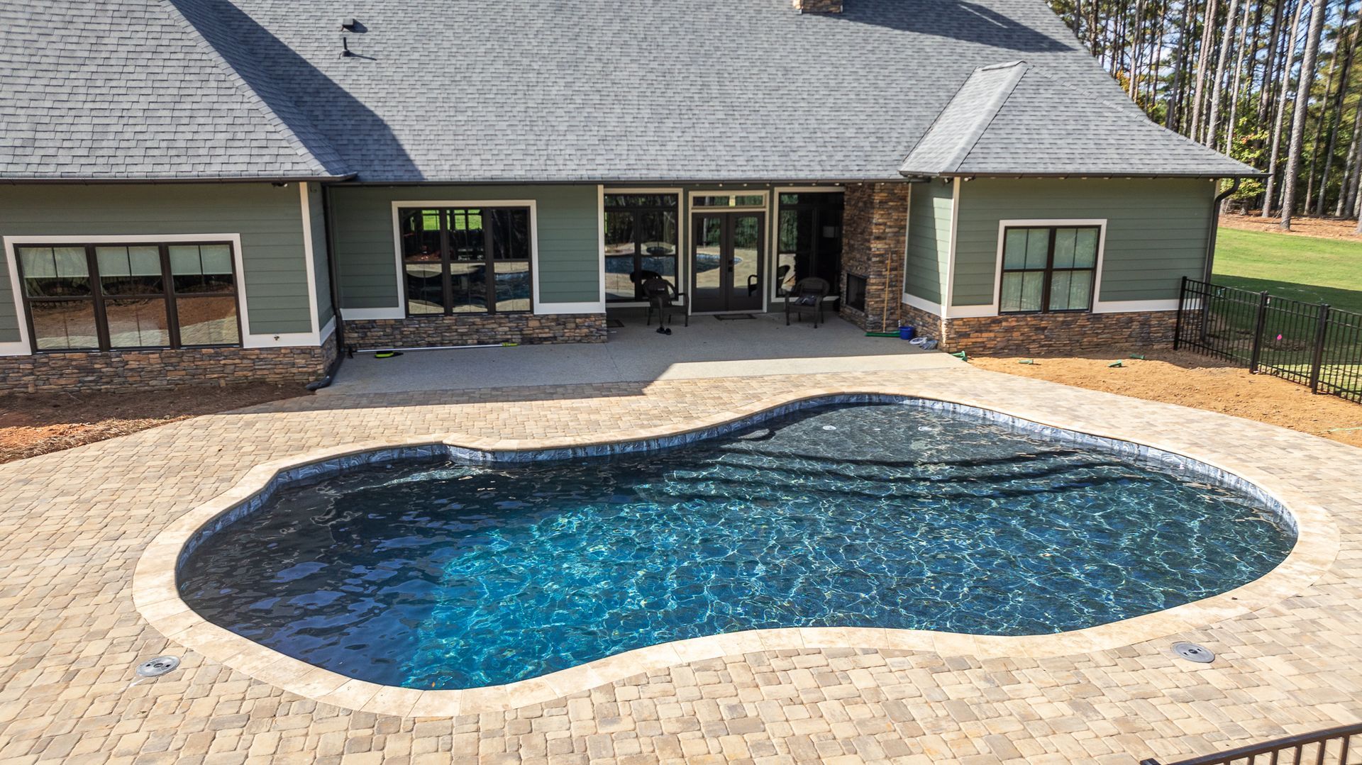 A large swimming pool is in front of a house.