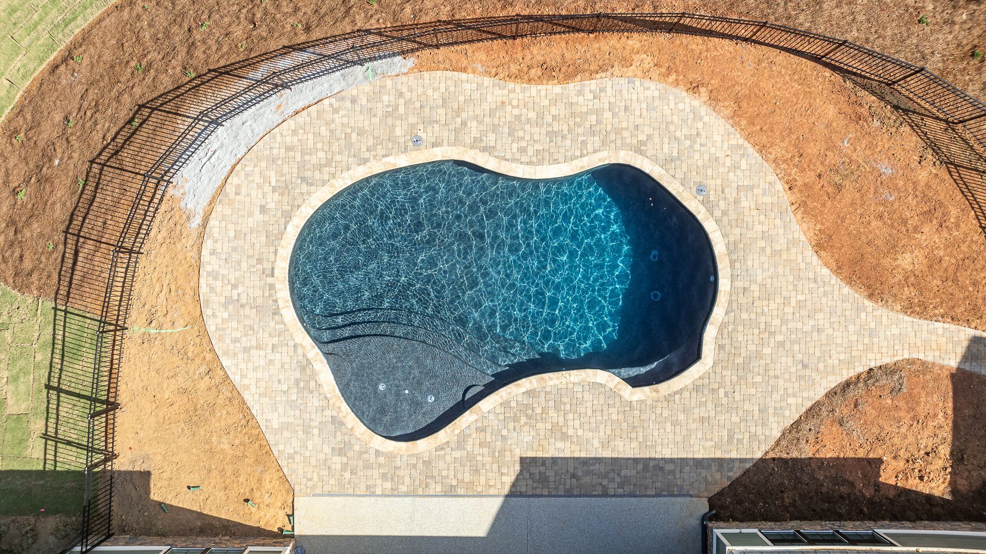 An aerial view of a large swimming pool in a backyard.