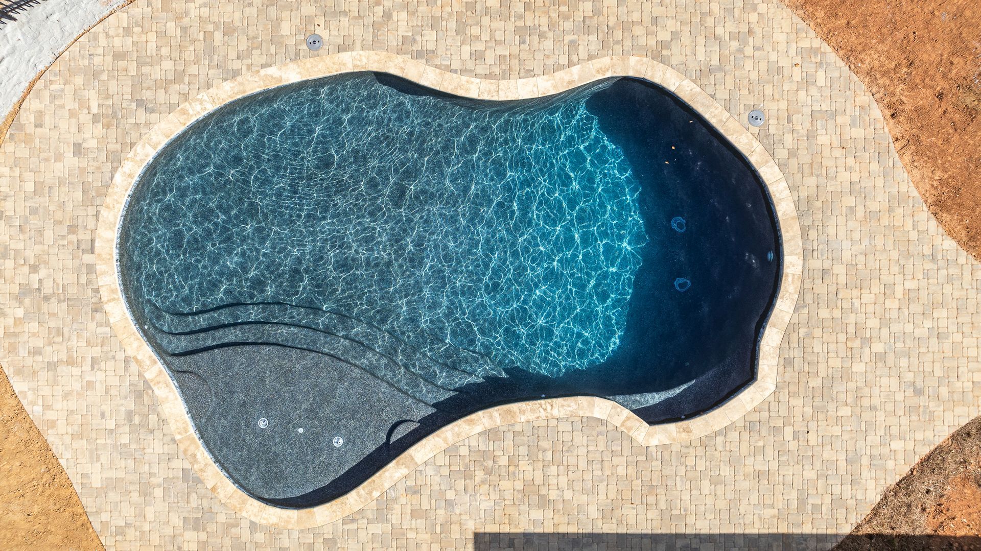 An aerial view of a swimming pool in the shape of a sponge.