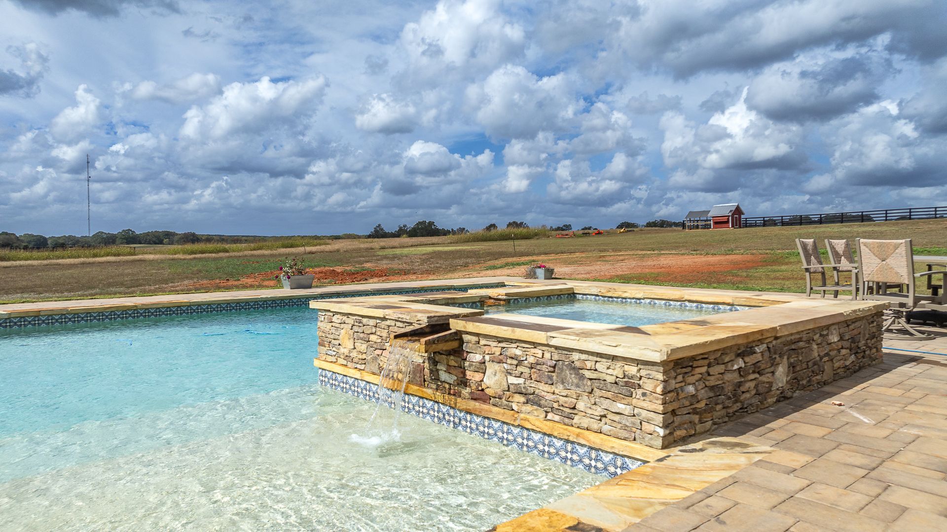 A large swimming pool with a hot tub in the middle of it.