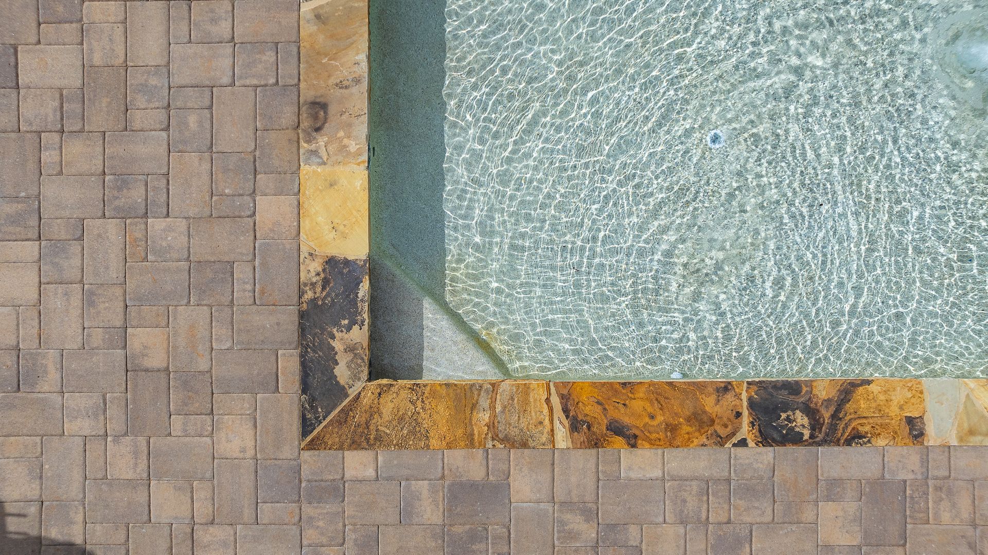 An aerial view of a swimming pool with a brick border