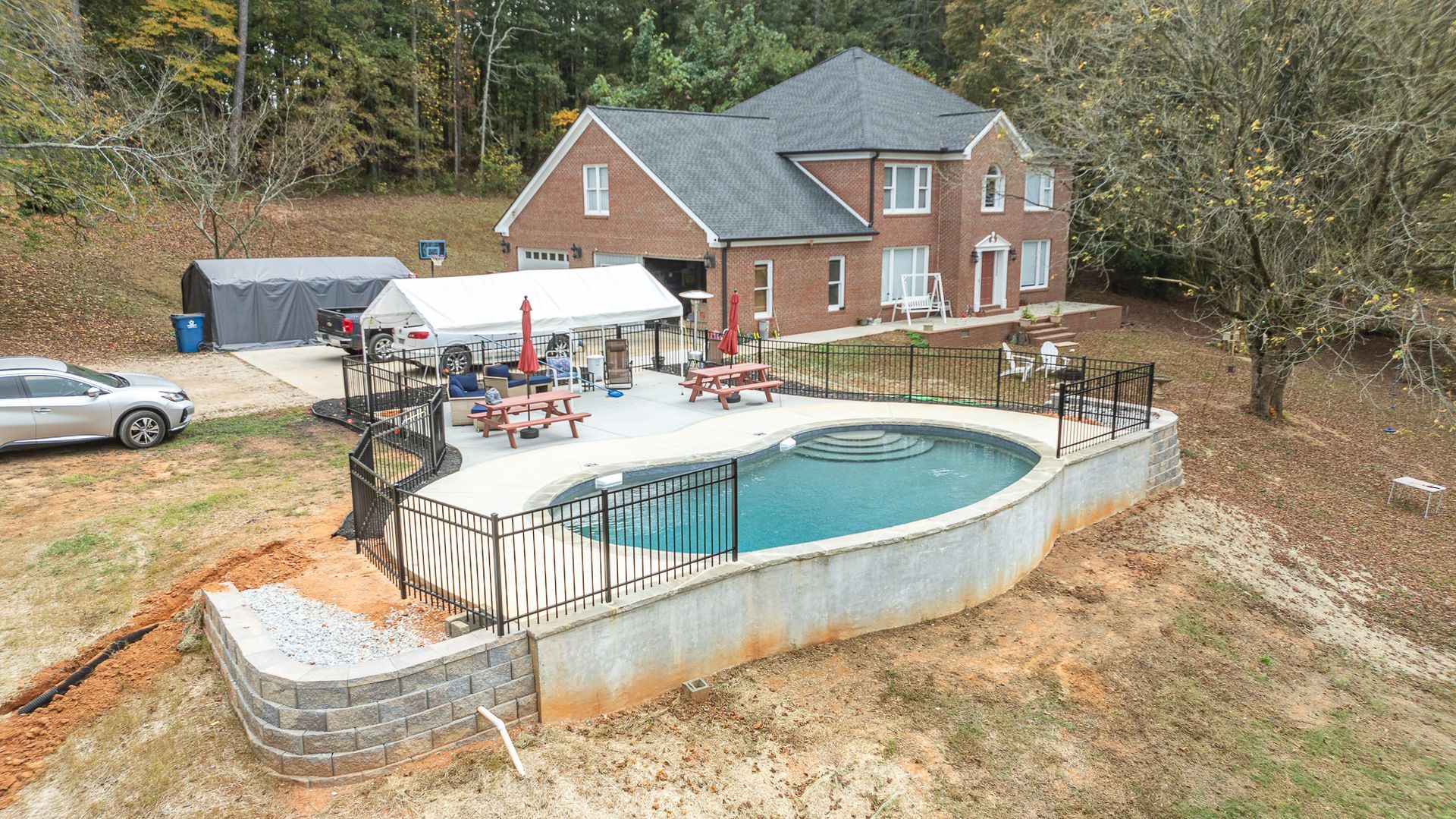 An aerial view of a house with a large swimming pool in front of it.