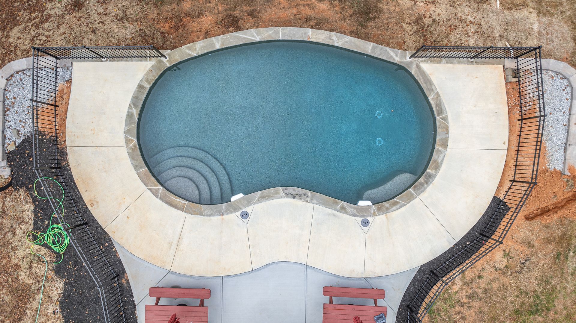 An aerial view of a large swimming pool in a backyard.