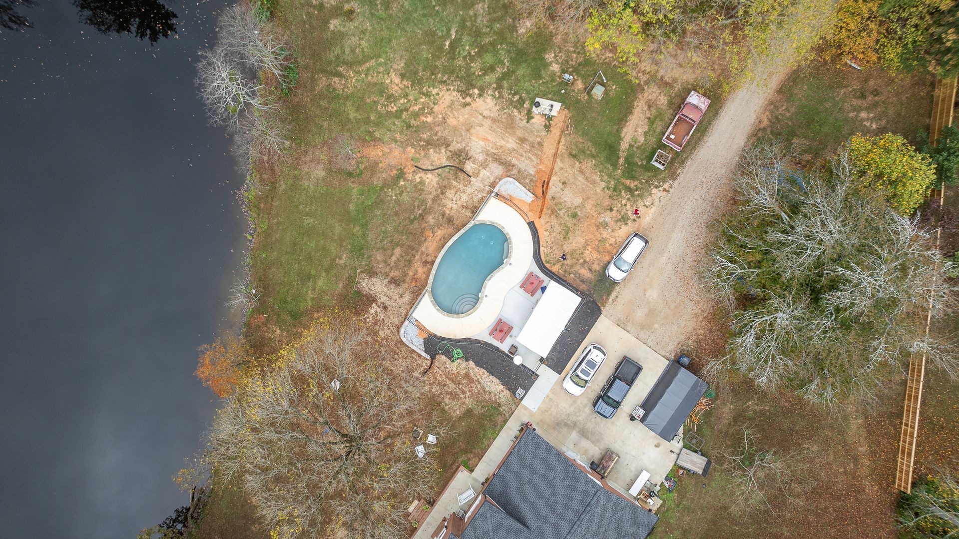 An aerial view of a house with a pool next to a lake.
