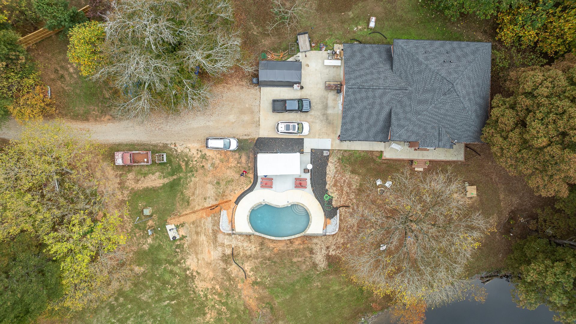 An aerial view of a house with a pool in the backyard surrounded by trees.