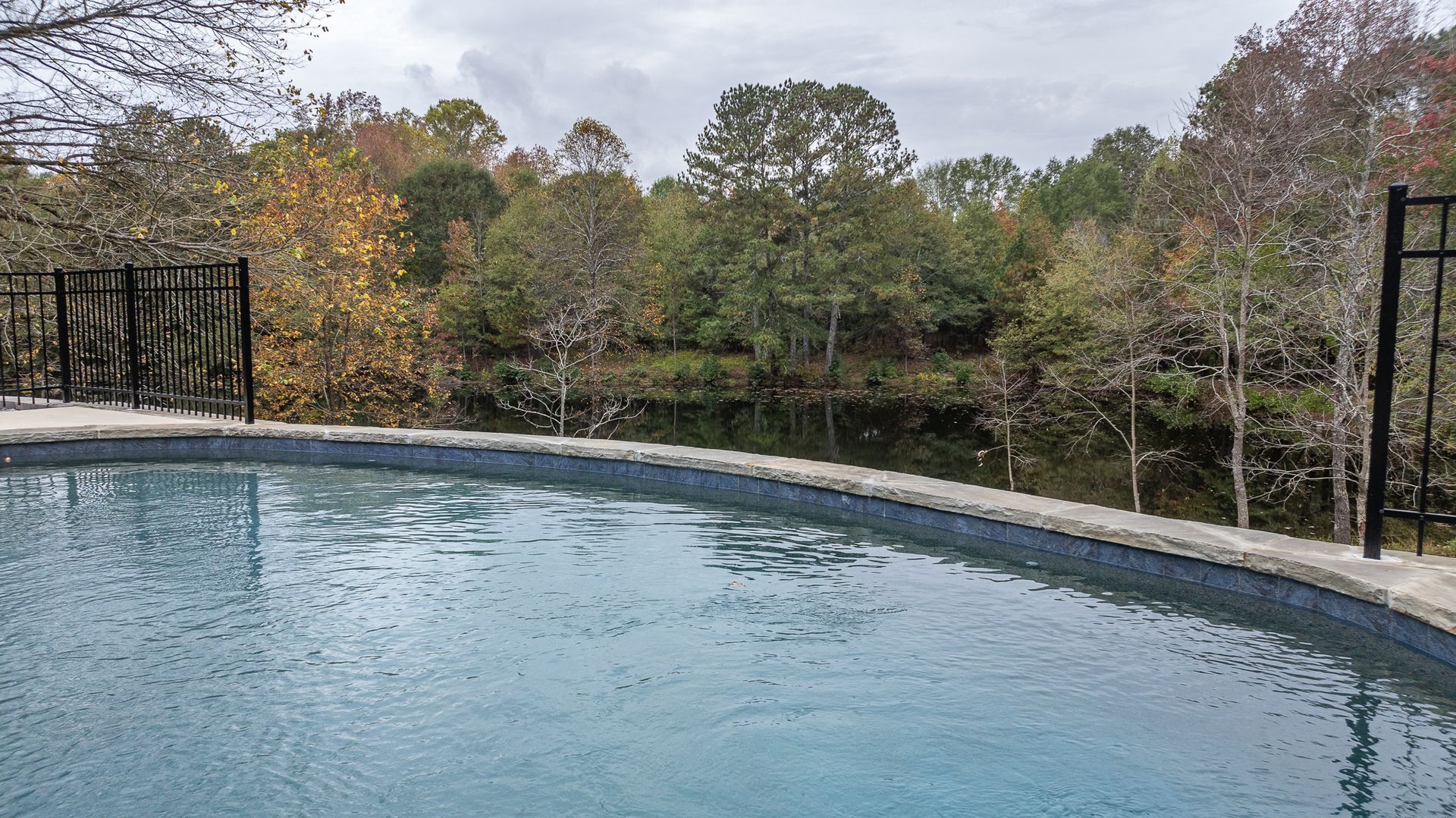 A large swimming pool surrounded by trees and a river.