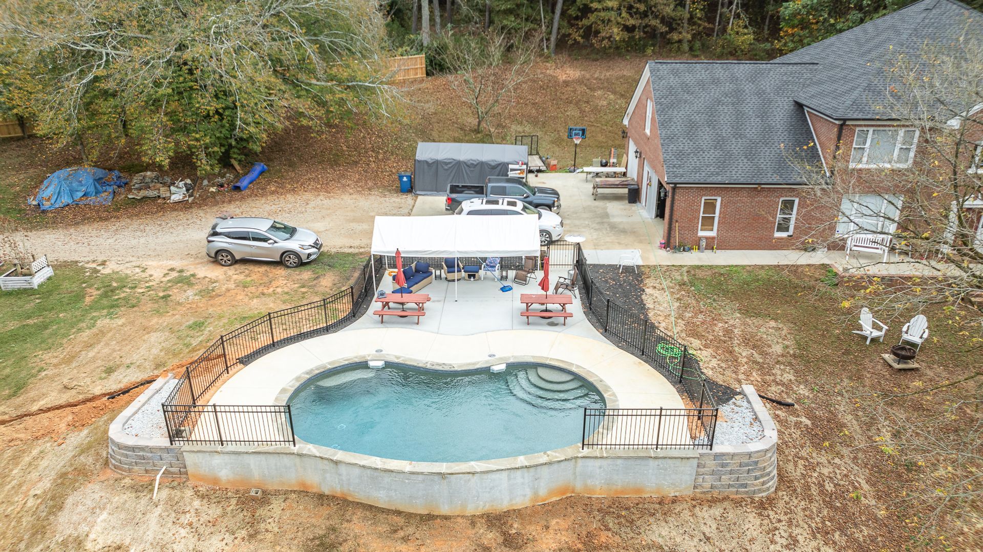 An aerial view of a large swimming pool in front of a house.