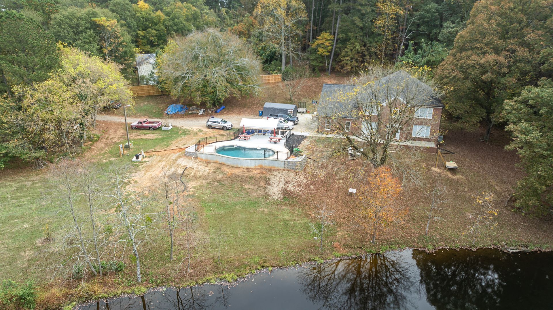 An aerial view of a house surrounded by trees and a pond.