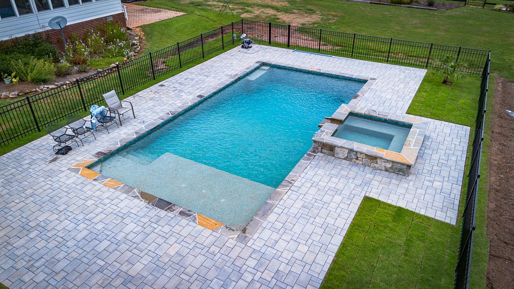 There is a large swimming pool in the backyard of a house.