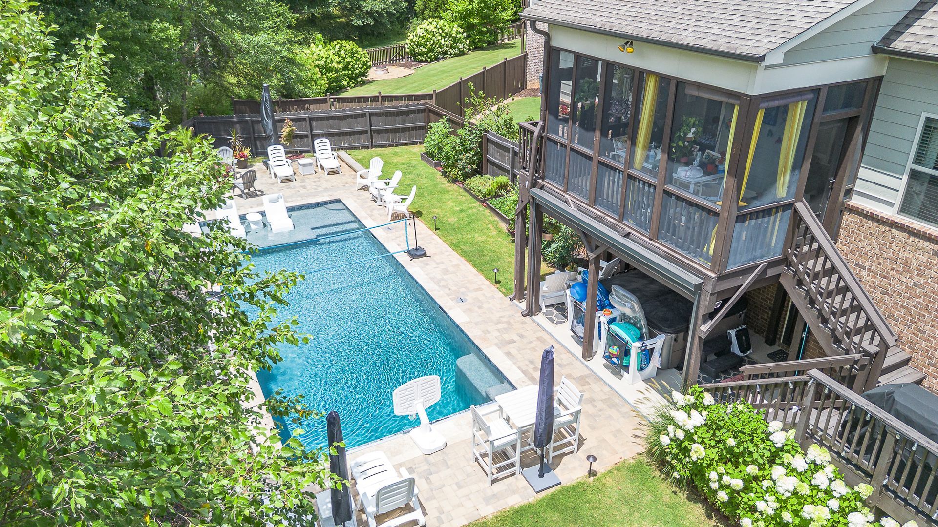 Poolside view: rectangular pool, screened porch, outdoor dining, and green lawn.