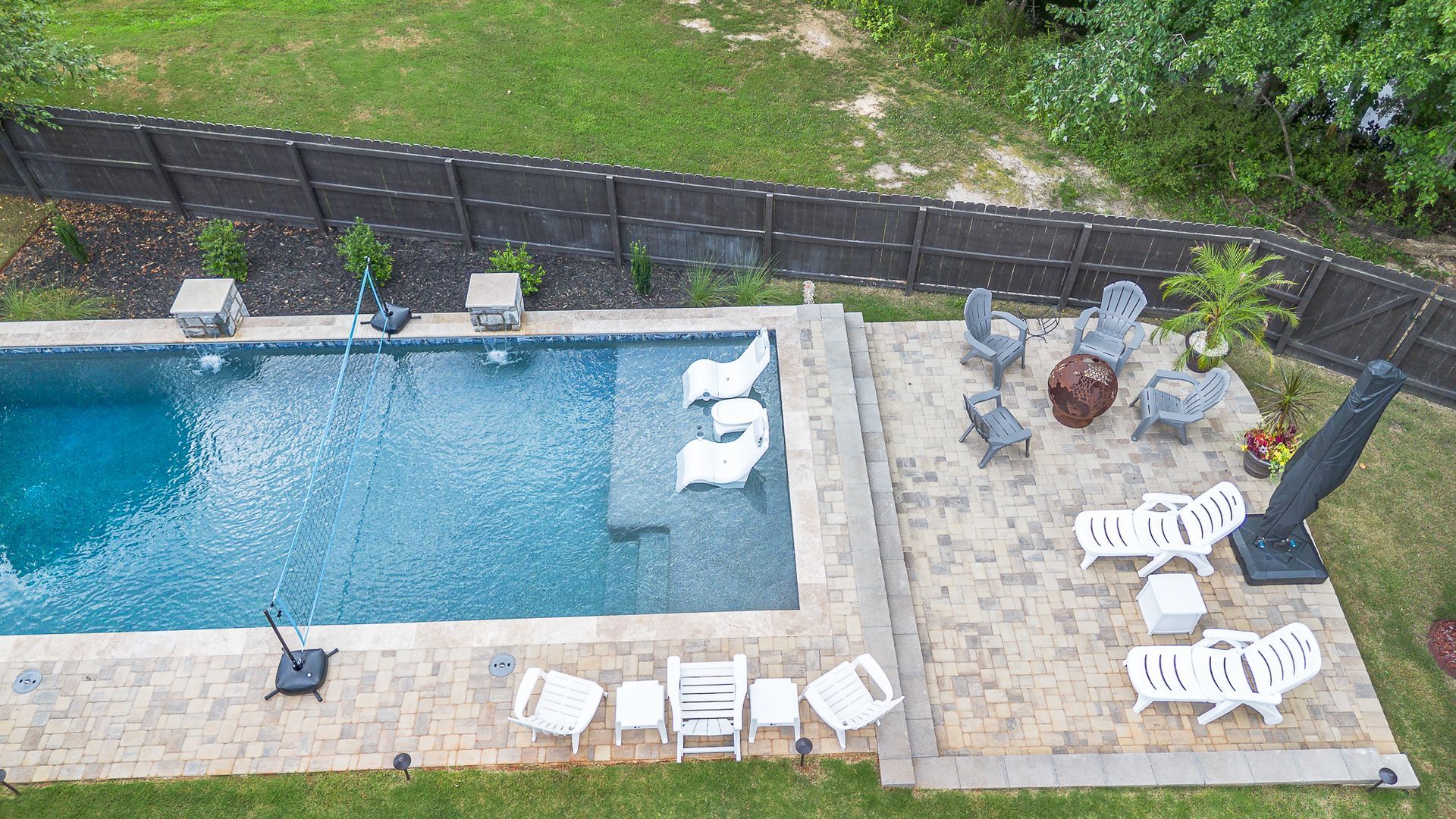 An aerial view of a large swimming pool surrounded by chairs and umbrellas.