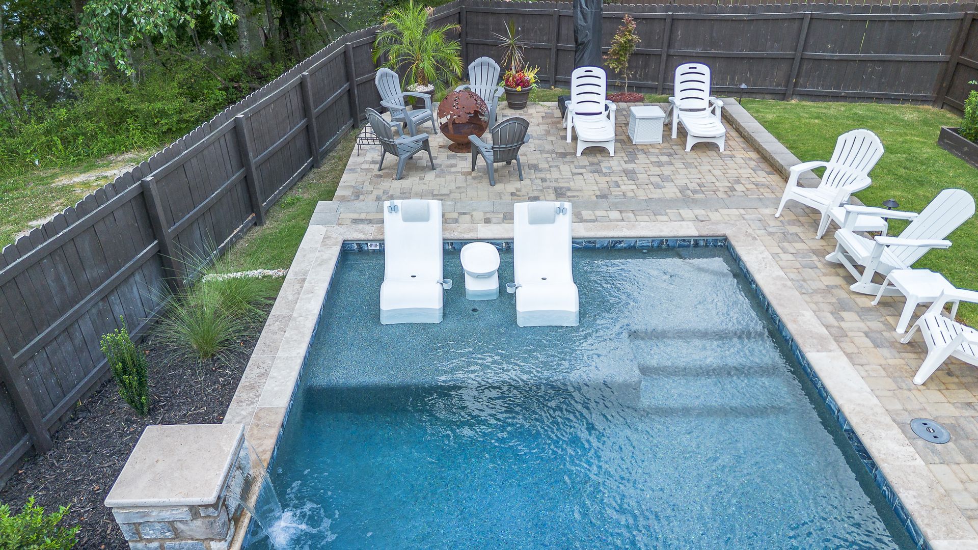 Overhead view of a backyard with a pool, lounge chairs, and patio area.