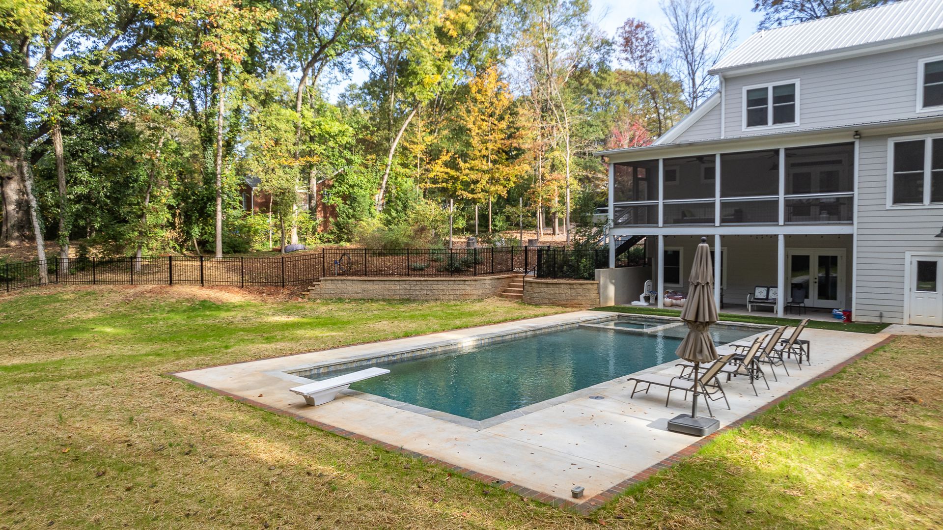 There is a large swimming pool in the backyard of a house.