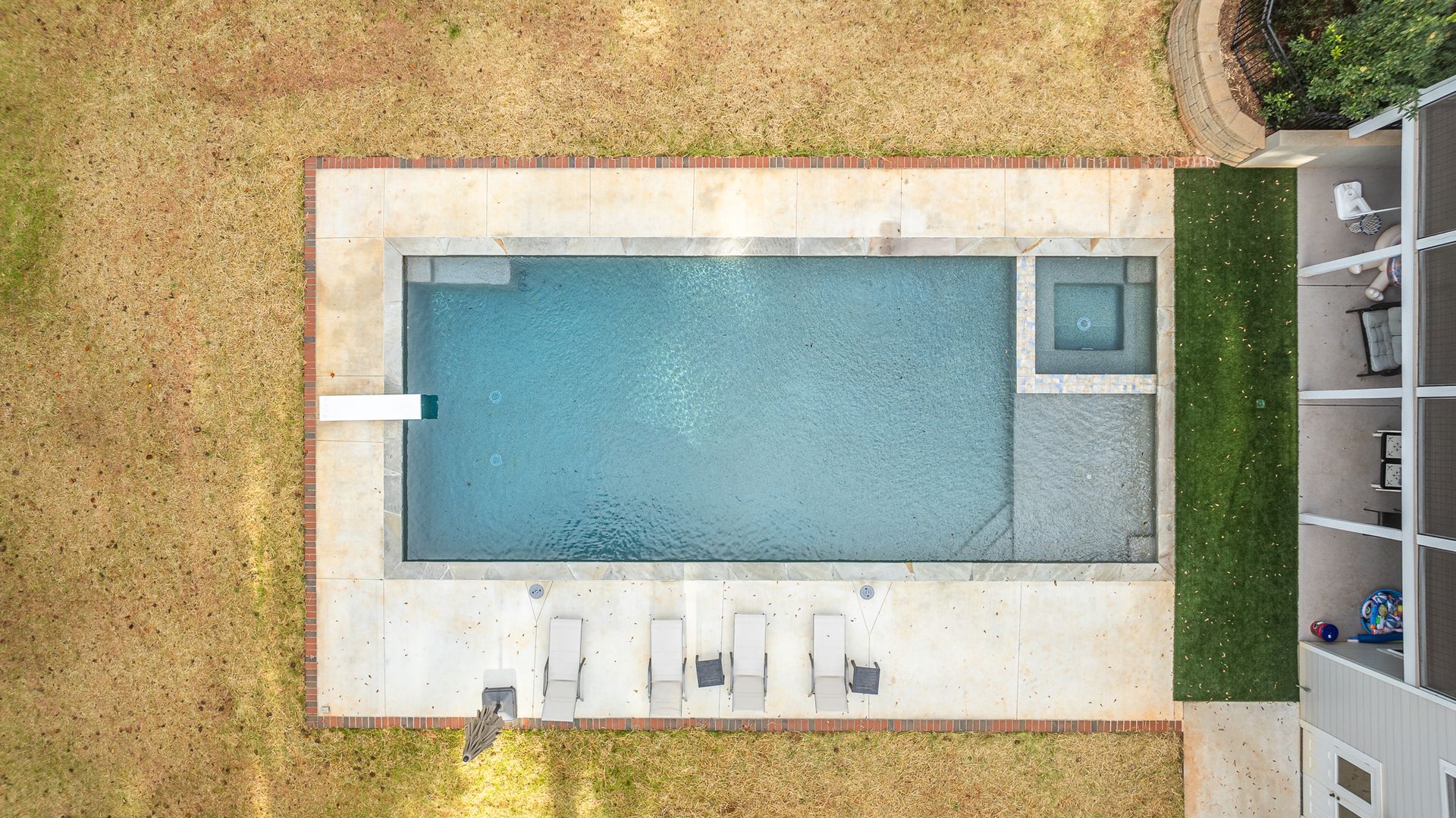 An aerial view of a large swimming pool in the backyard of a house.