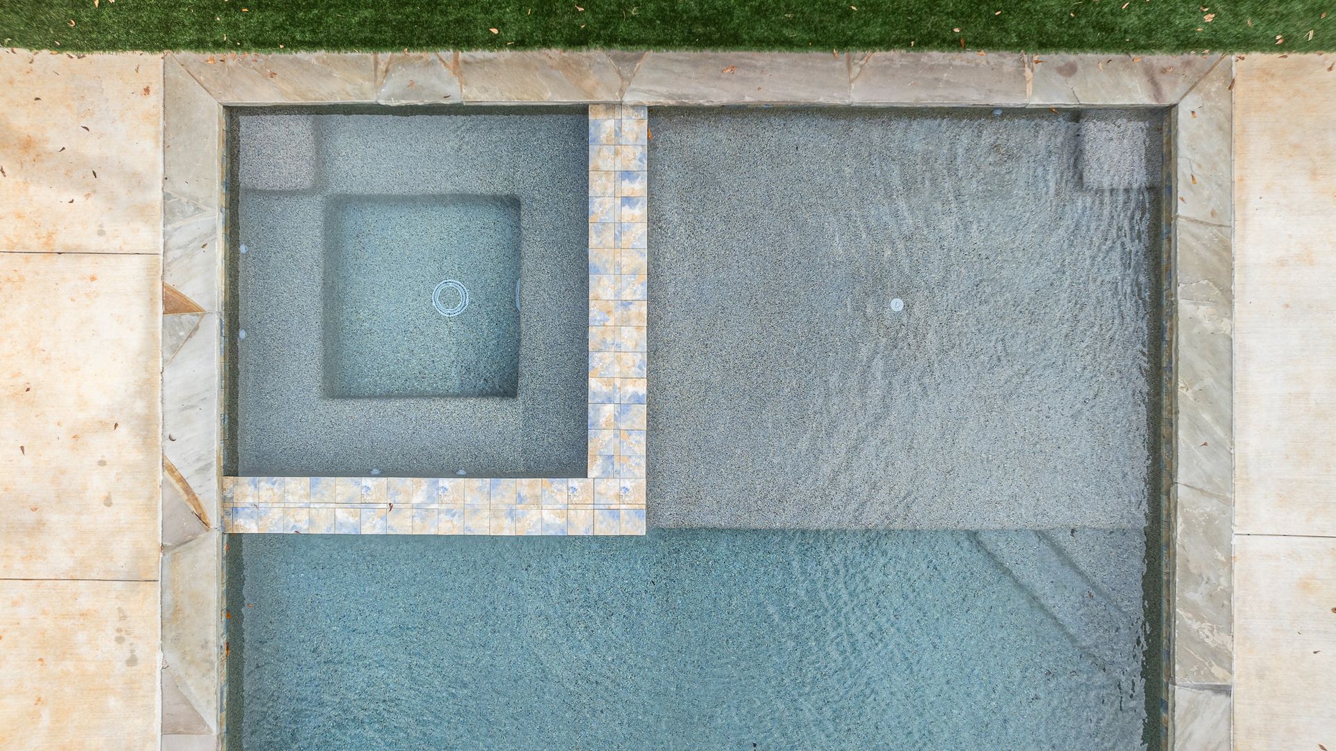 An aerial view of a swimming pool surrounded by grass.