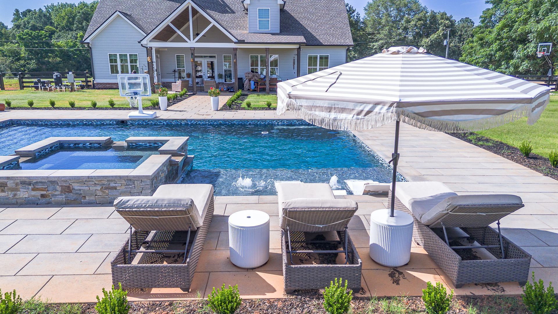 A large swimming pool with chairs and umbrellas in front of a house.