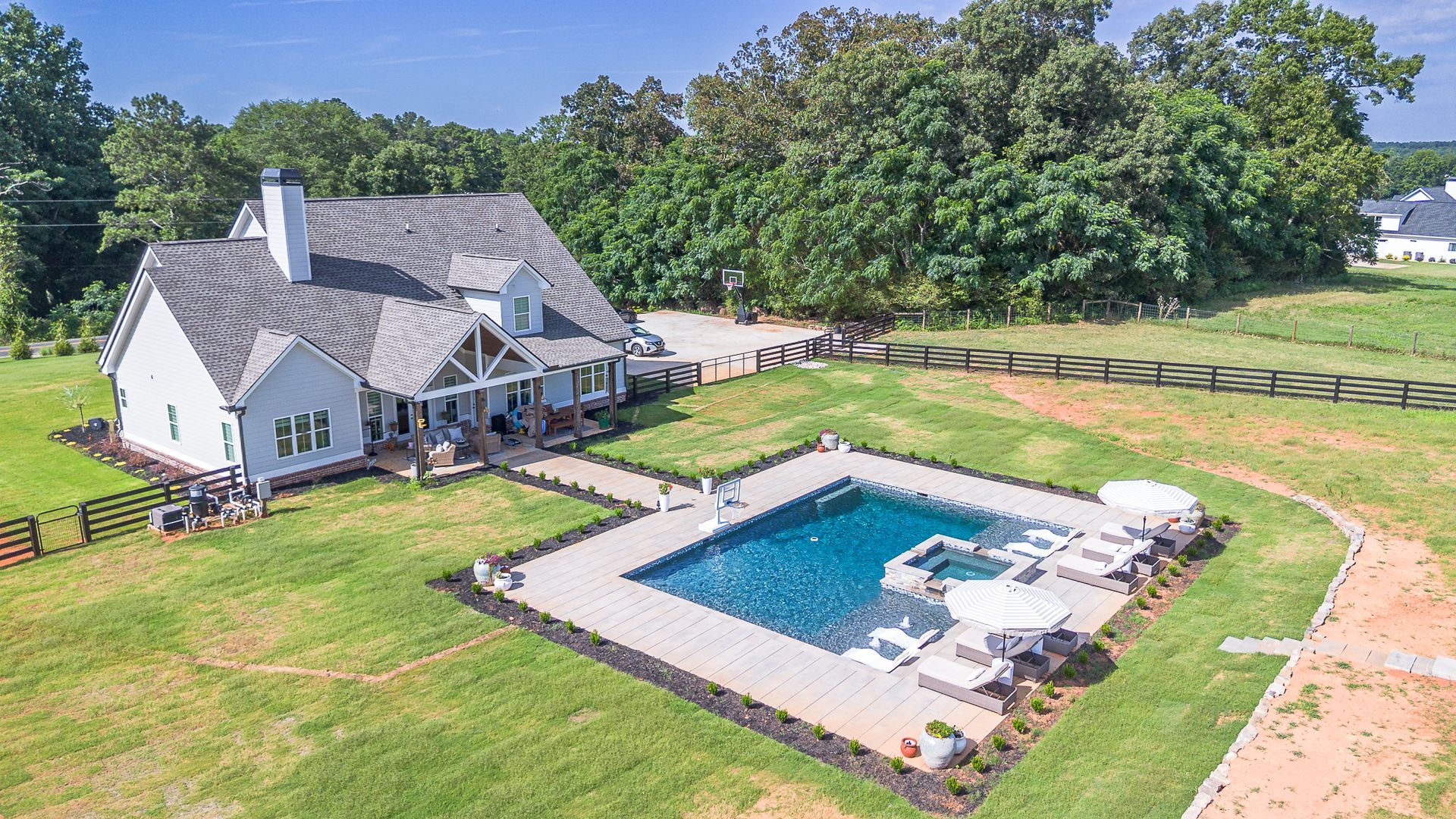 House with pool in yard, surrounded by trees and grass.