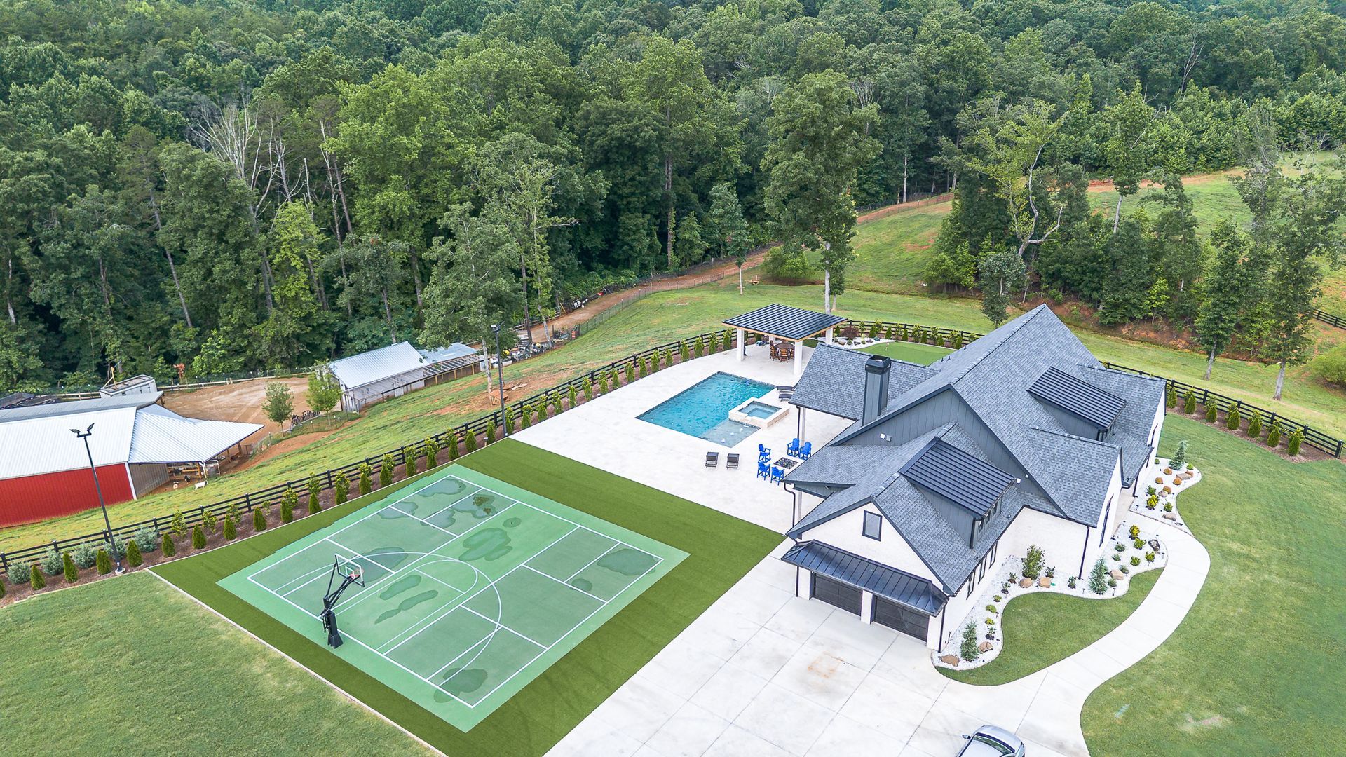 An aerial view of a large house with a tennis court and a swimming pool.