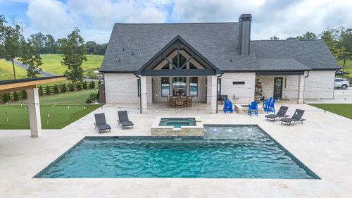 A large swimming pool is surrounded by a brick patio.