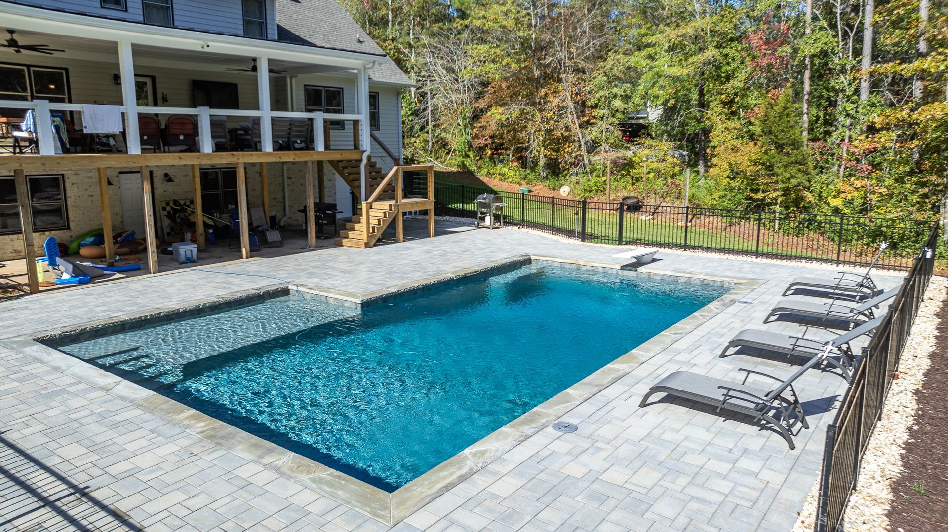 There is a large swimming pool in the backyard of a house.
