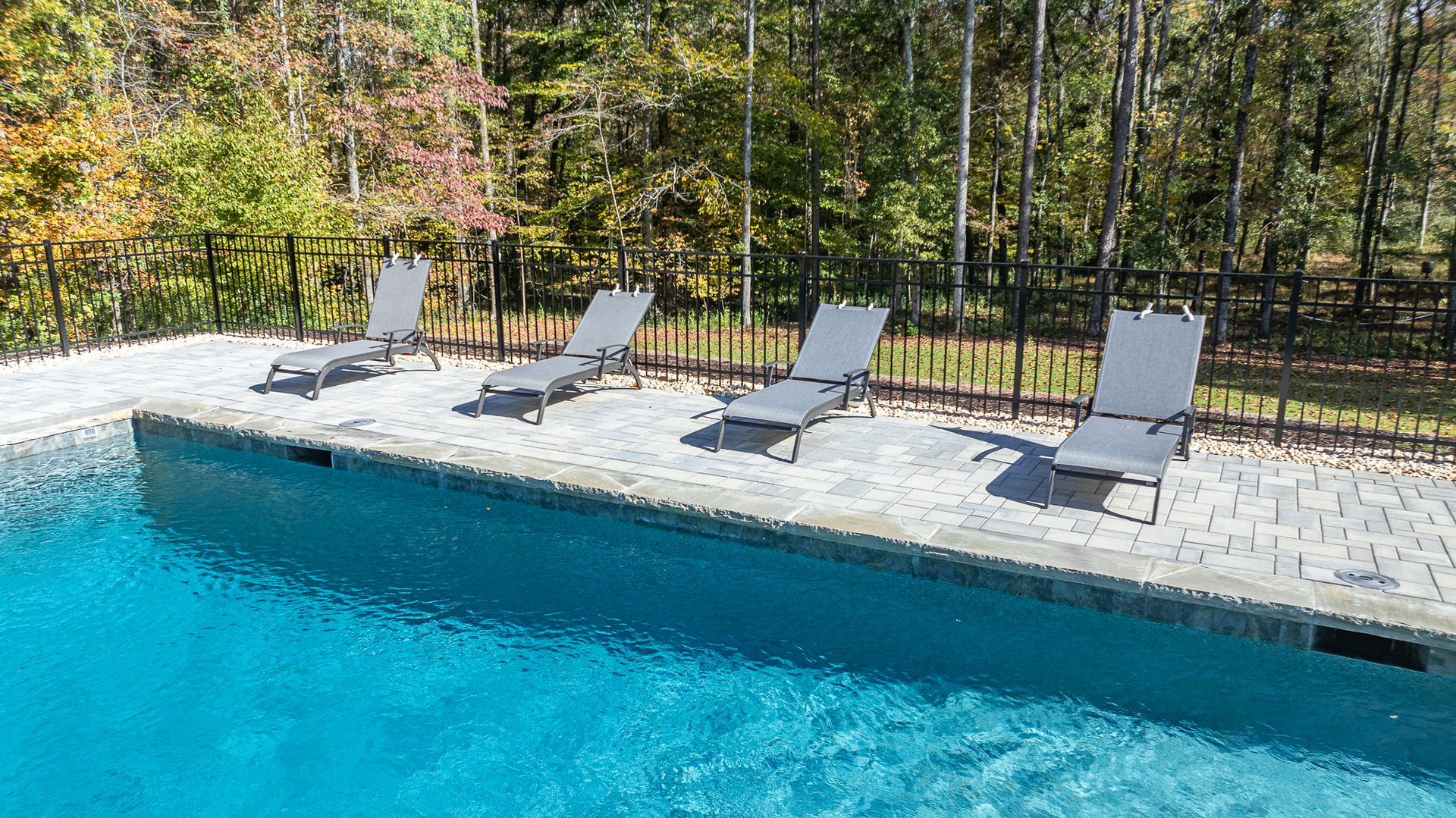 A row of lounge chairs sitting next to a swimming pool.
