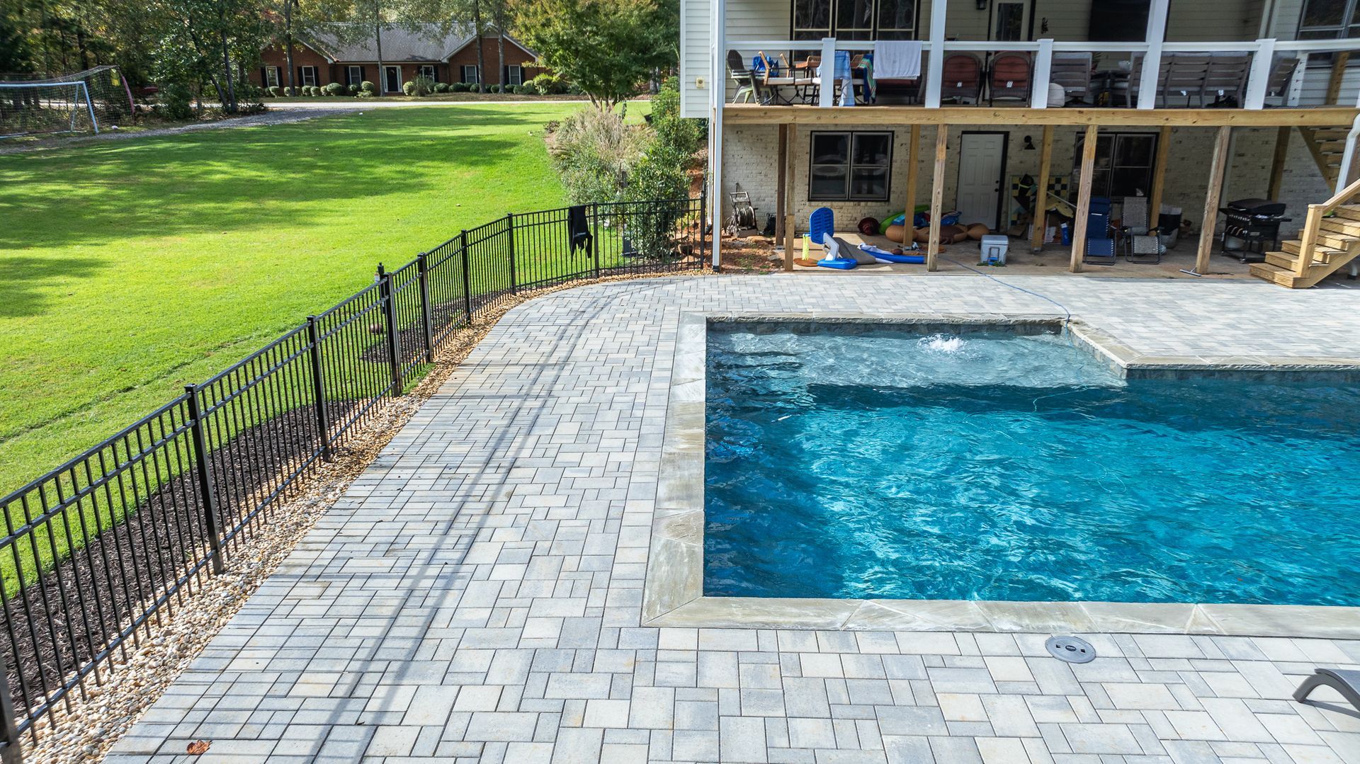 There is a large swimming pool in the backyard of a house.