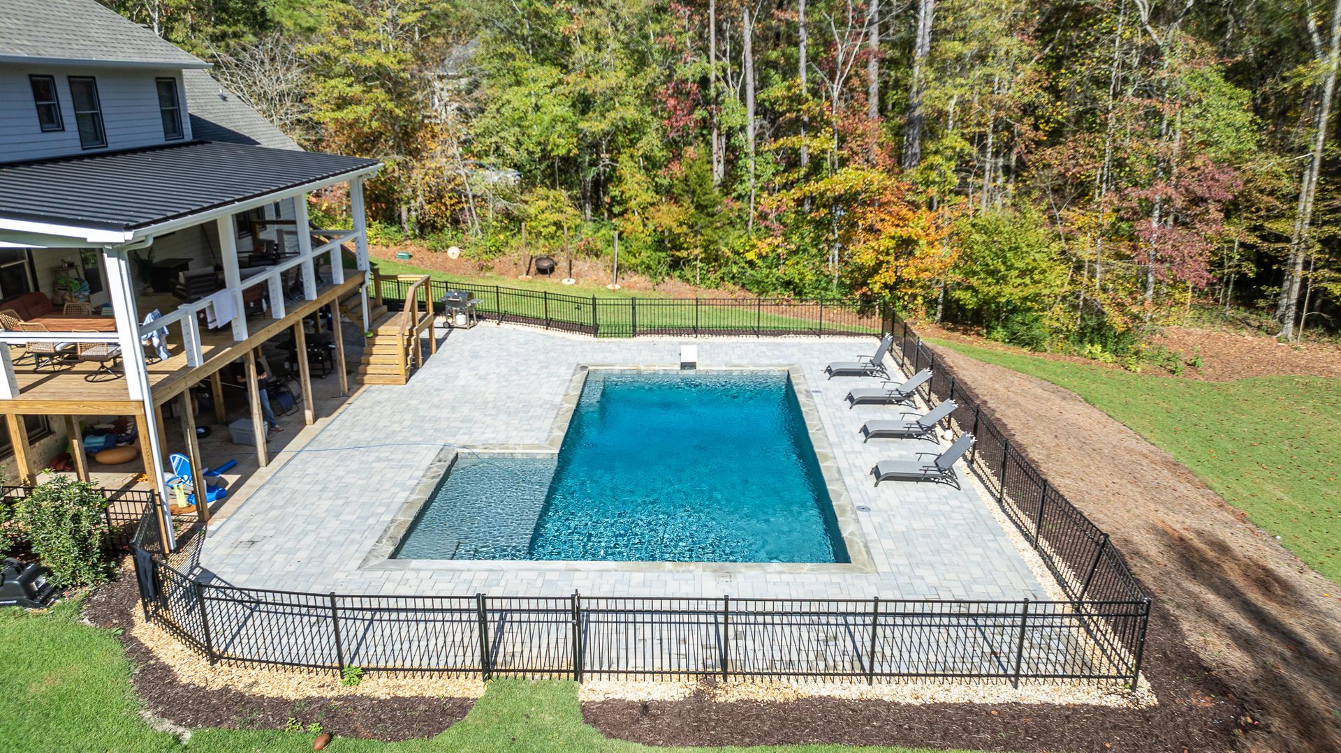 An aerial view of a large swimming pool in the backyard of a house.