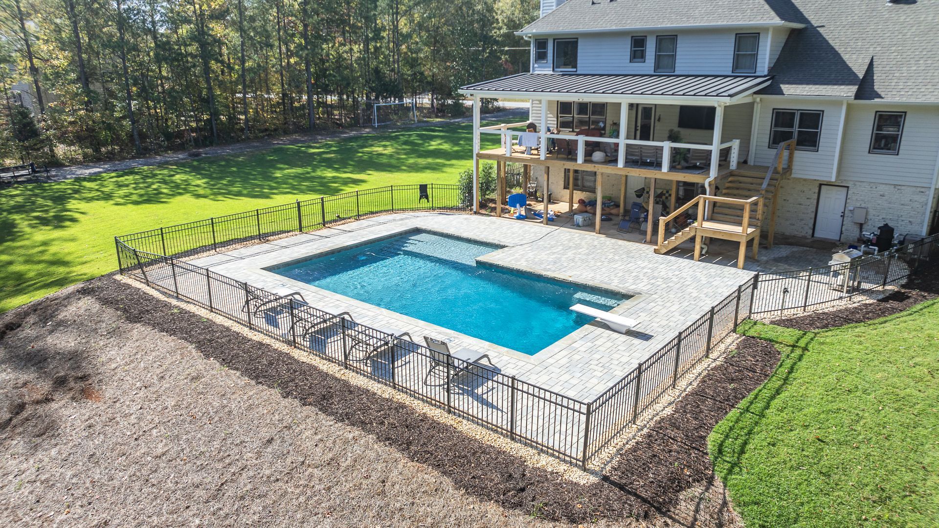 An aerial view of a large swimming pool in the backyard of a house.