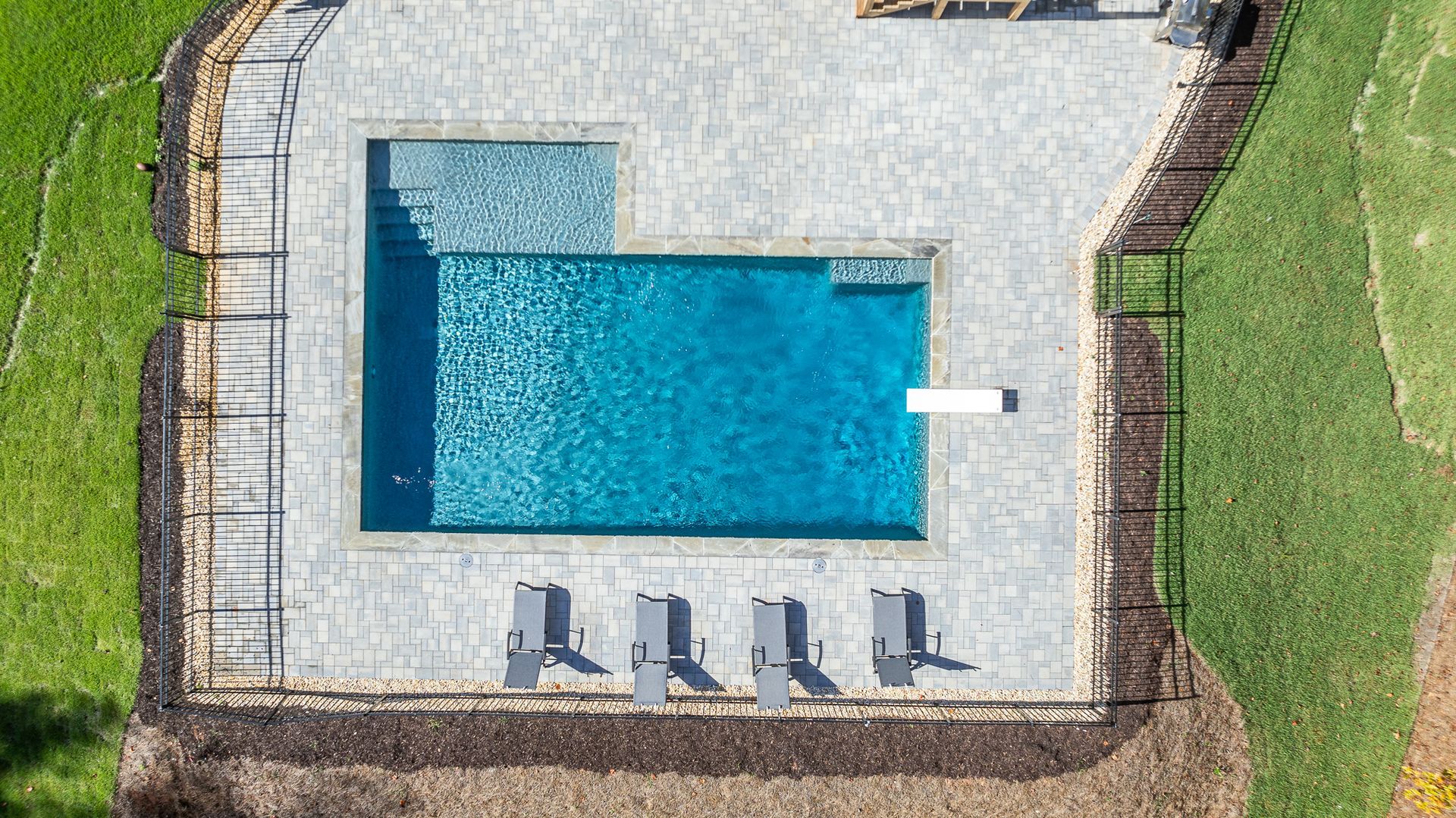 An aerial view of a large swimming pool surrounded by chairs and a fence.