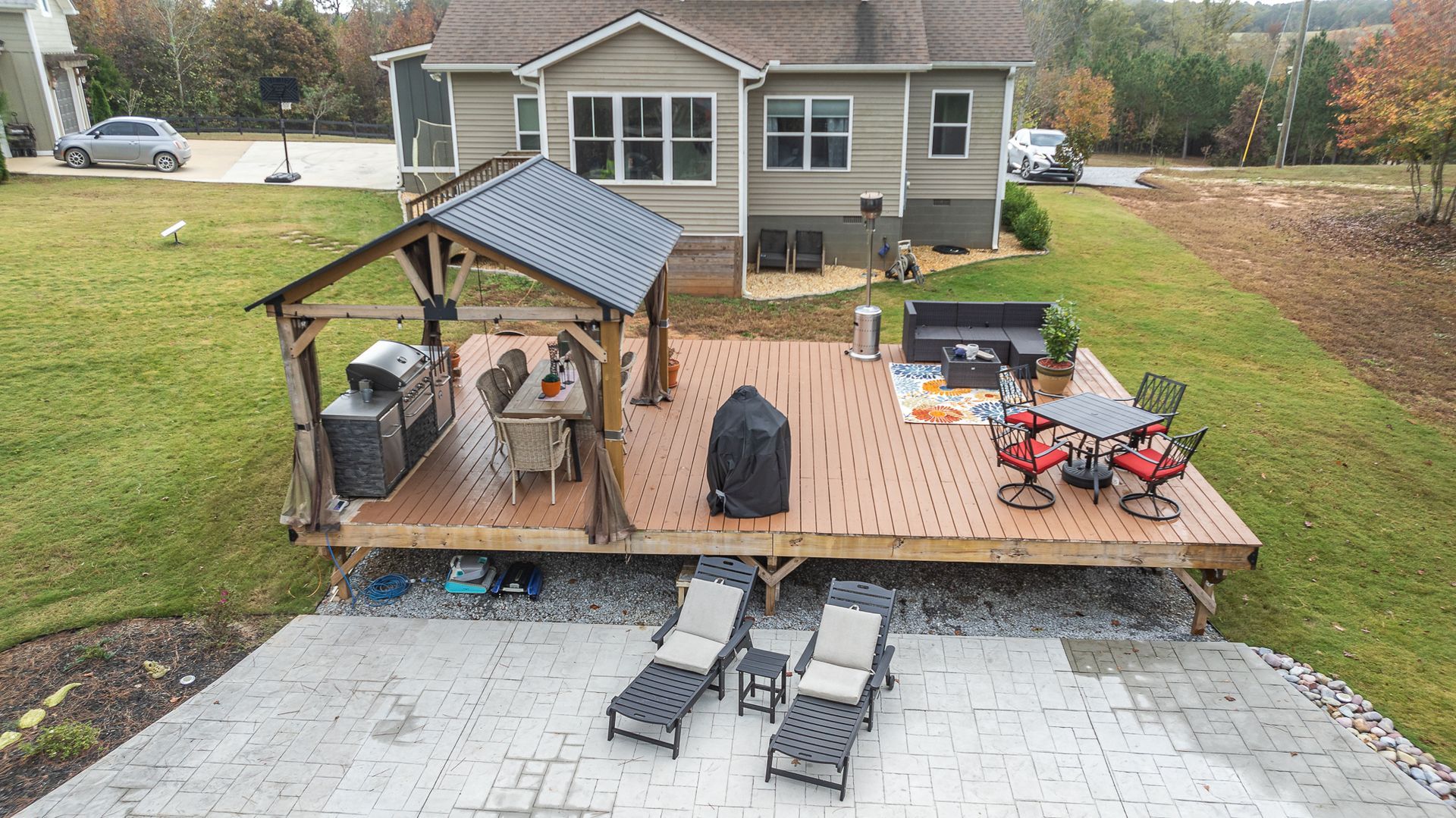 An aerial view of a large deck with a gazebo and chairs in front of a house.