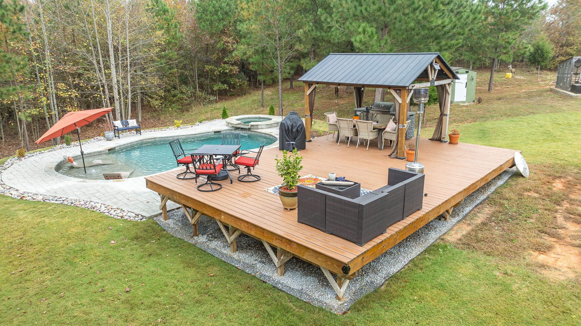 An aerial view of a large wooden deck with a swimming pool in the background.